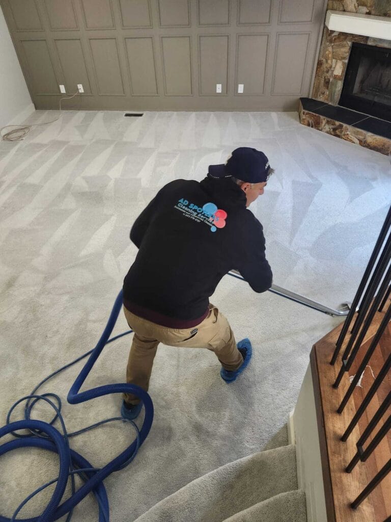 AD Spotless technician steam cleaning a light-coloured carpet beside a staircase