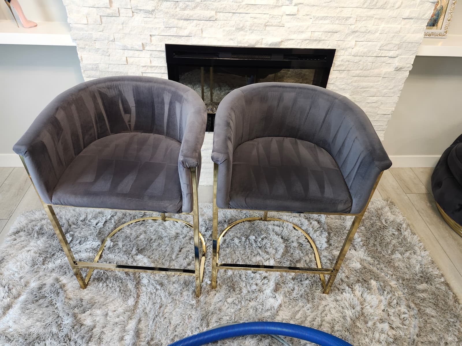 Two grey upholstered armchairs in front of a fireplace, with cleaning hose visible