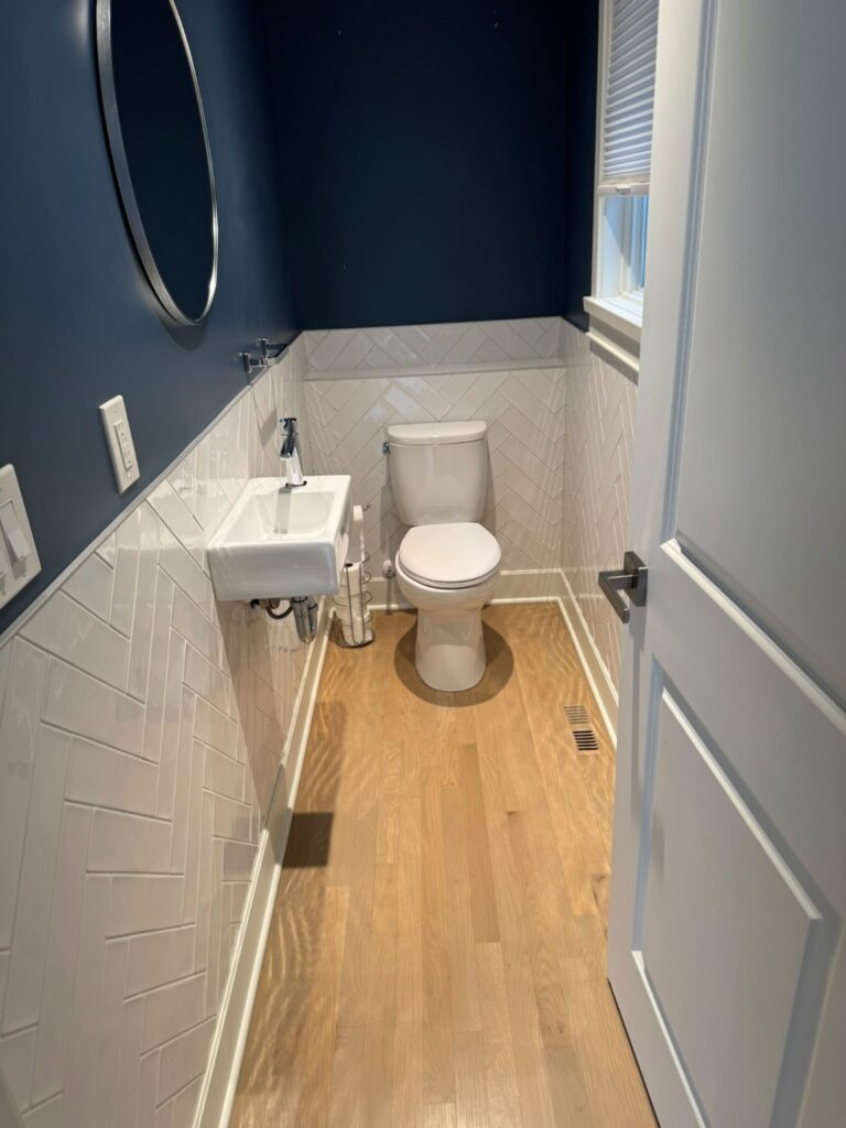 Bathroom with a wall-mounted sink, toilet, tiled lower walls and wood flooring