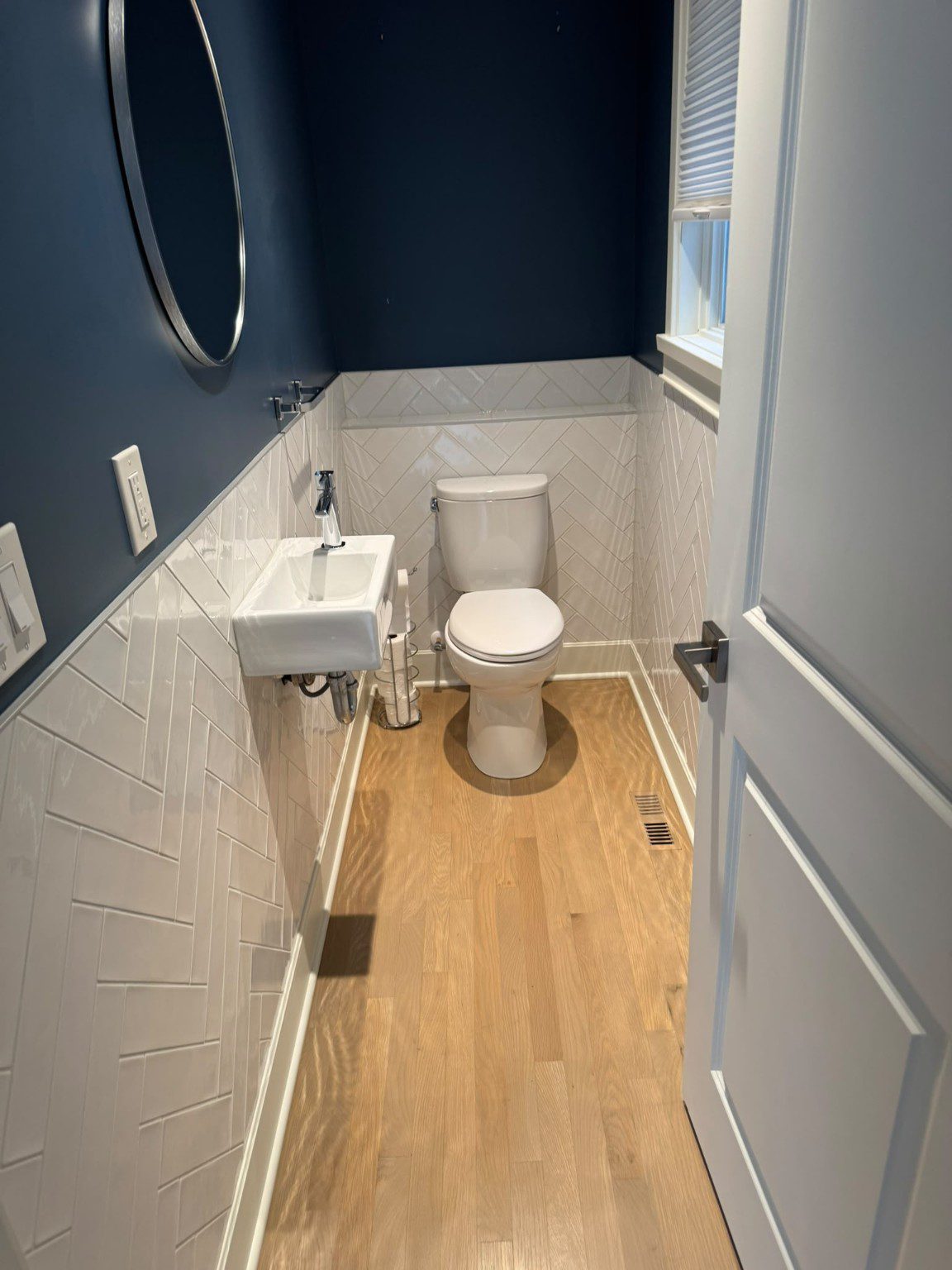 Bathroom with blue walls, white wall tiles, a compact sink and a toilet