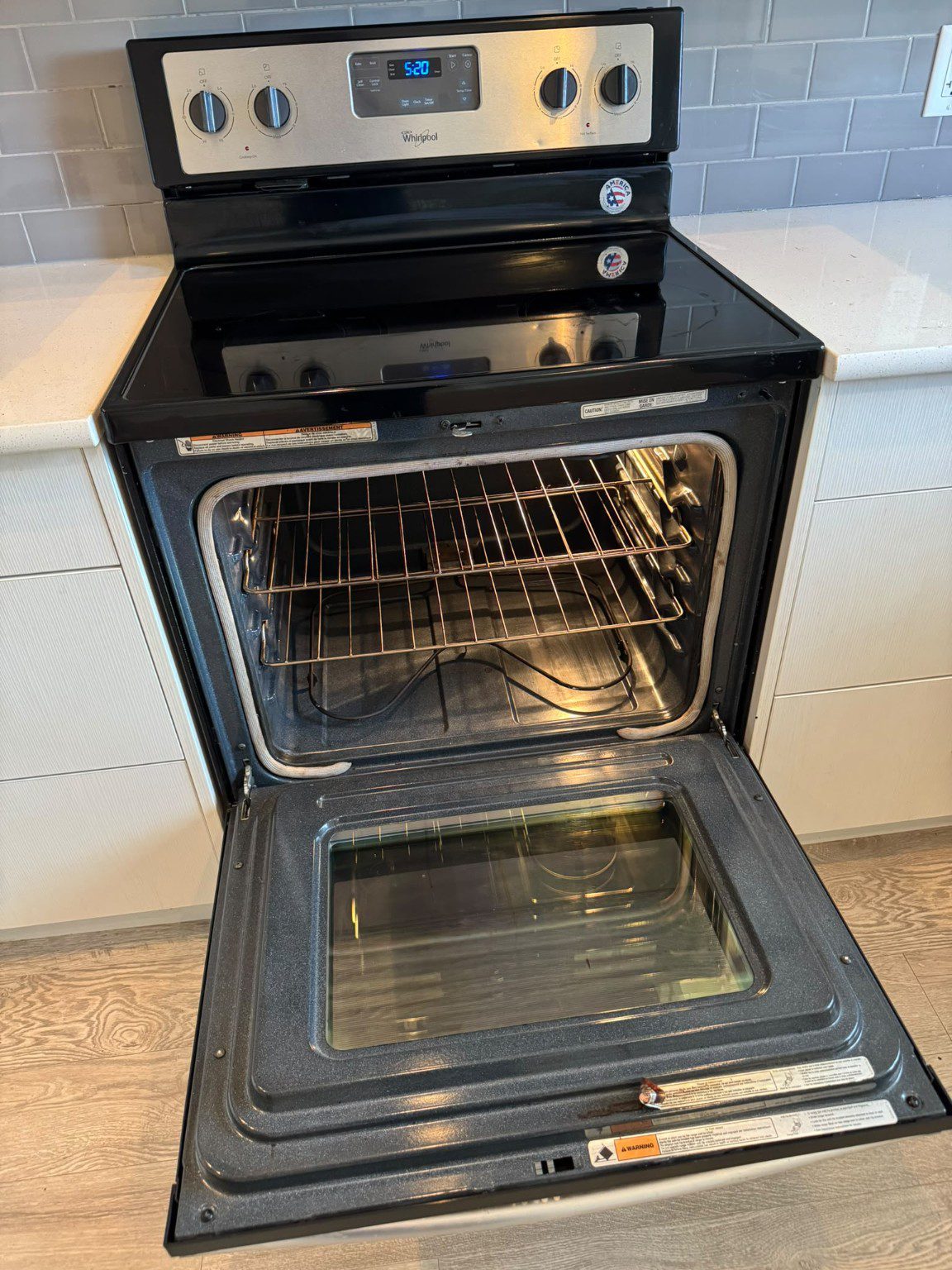Freestanding range with the oven door open, showing the racks, interior and glass cooktop