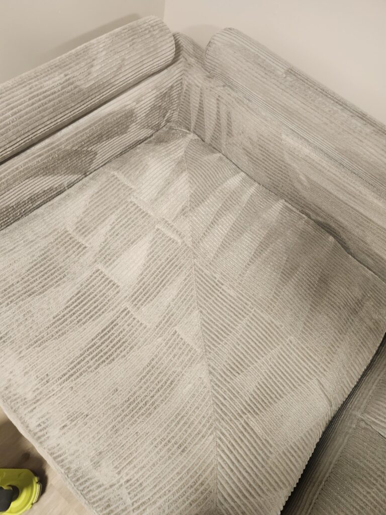 Close-up of a cream textured sofa showing the seat, back cushions and corner seams