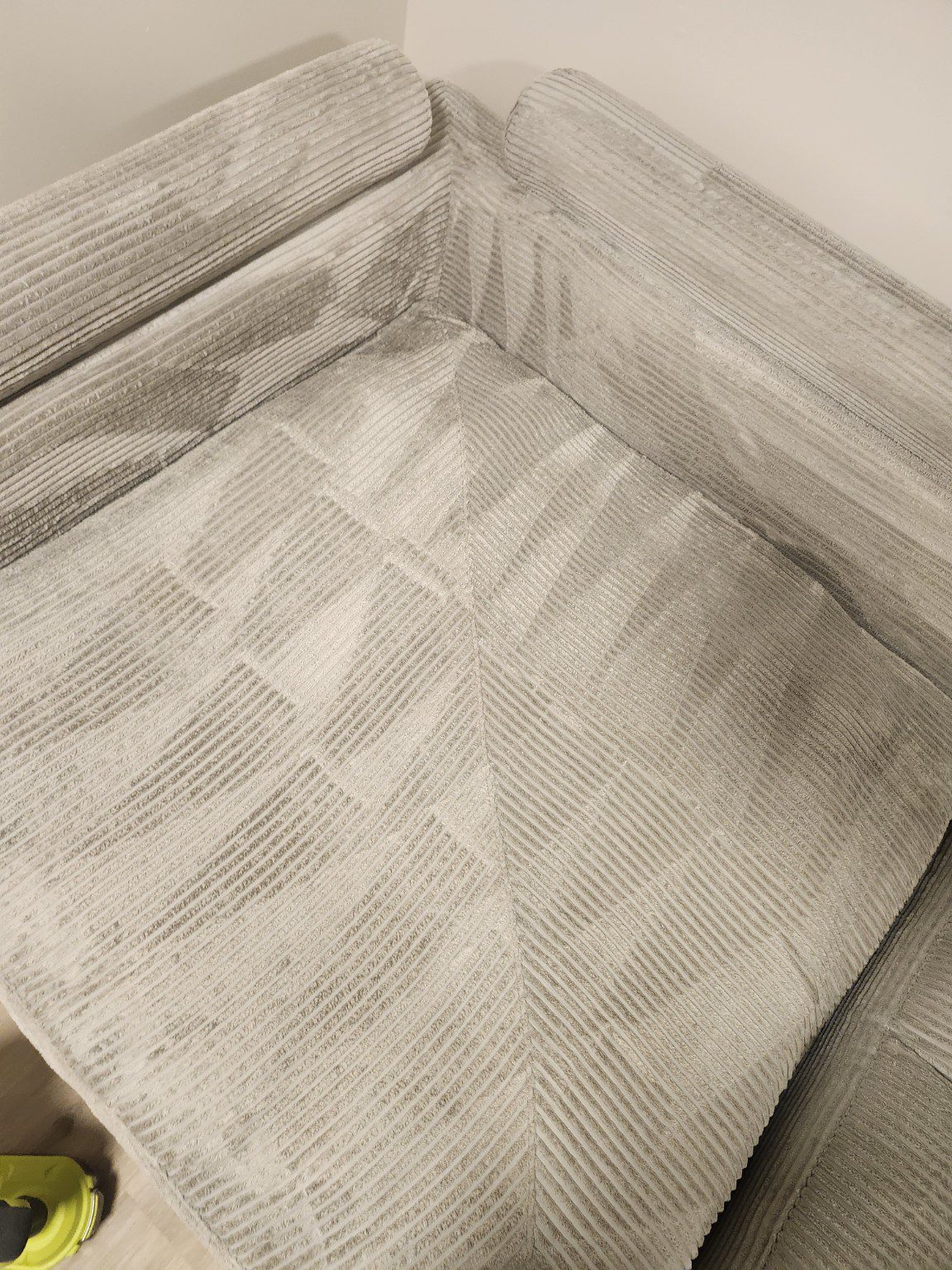 Close-up of a cream textured sofa showing the seat, back cushions and corner seams
